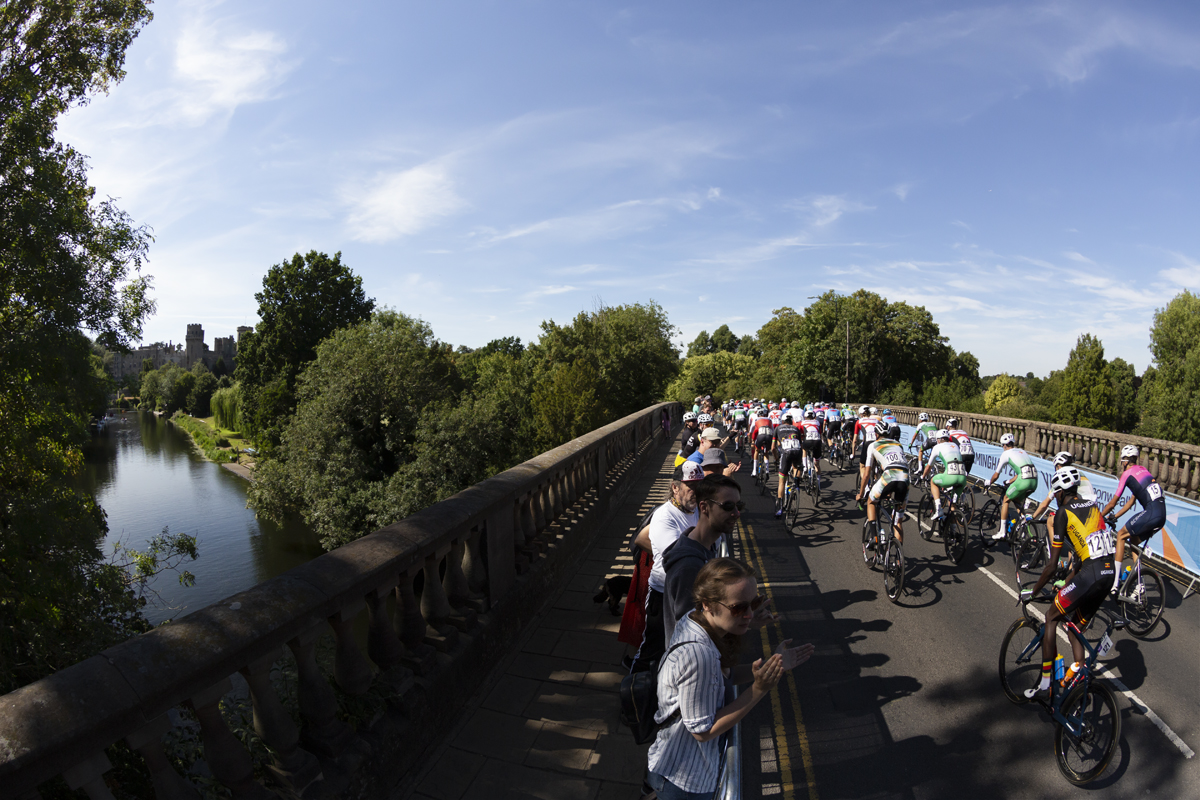 Birmingham 2022 - XXII Commonwealth Games - Men’s Road Race - Riders cross the River Avon on Castle Bridge with Warwick Castle in background