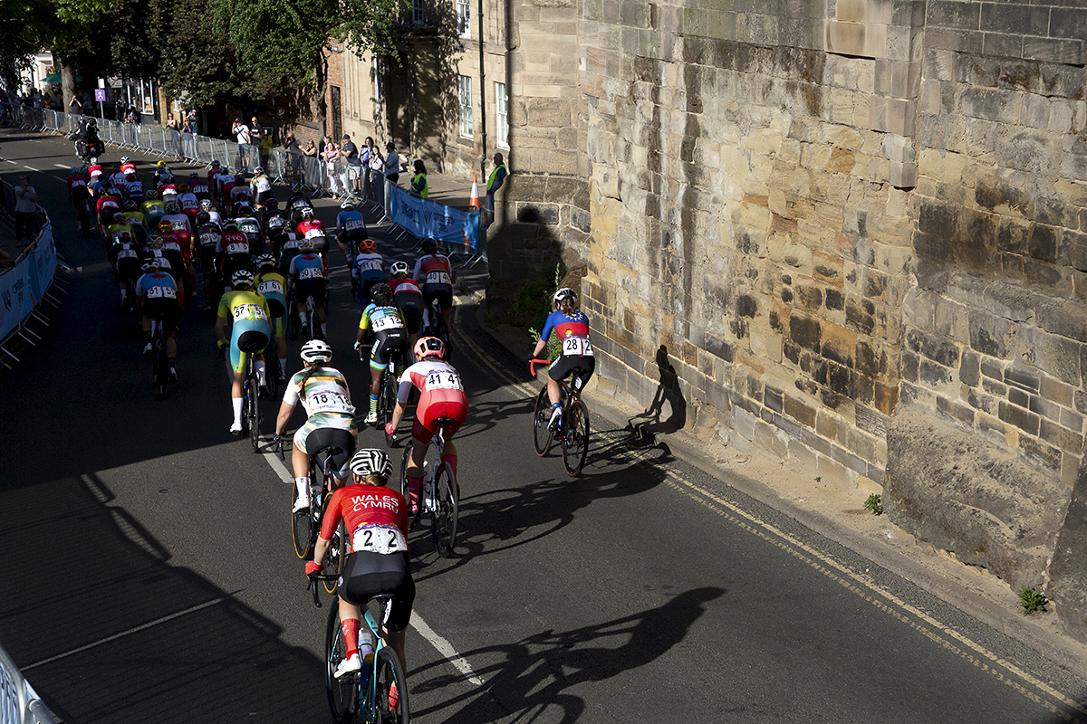 Birmingham 2022 - XXII Commonwealth Games - Women’s Road Race - The peloton passes by the old stone wall of West Gate in Warwick