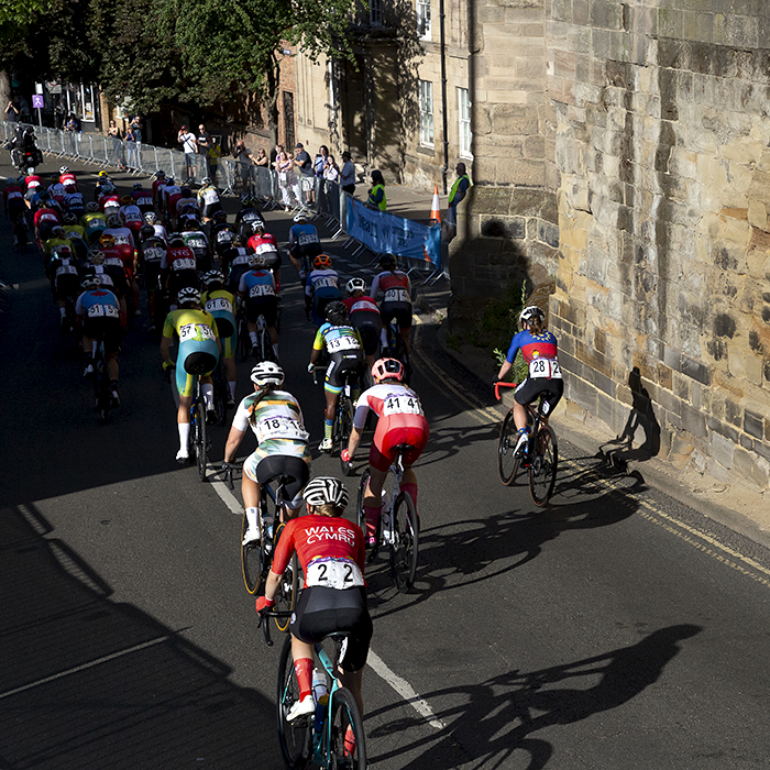 Birmingham 2022 - XXII Commonwealth Games - Women’s Road Race - The peloton passes by the old stone wall of West Gate in Warwick