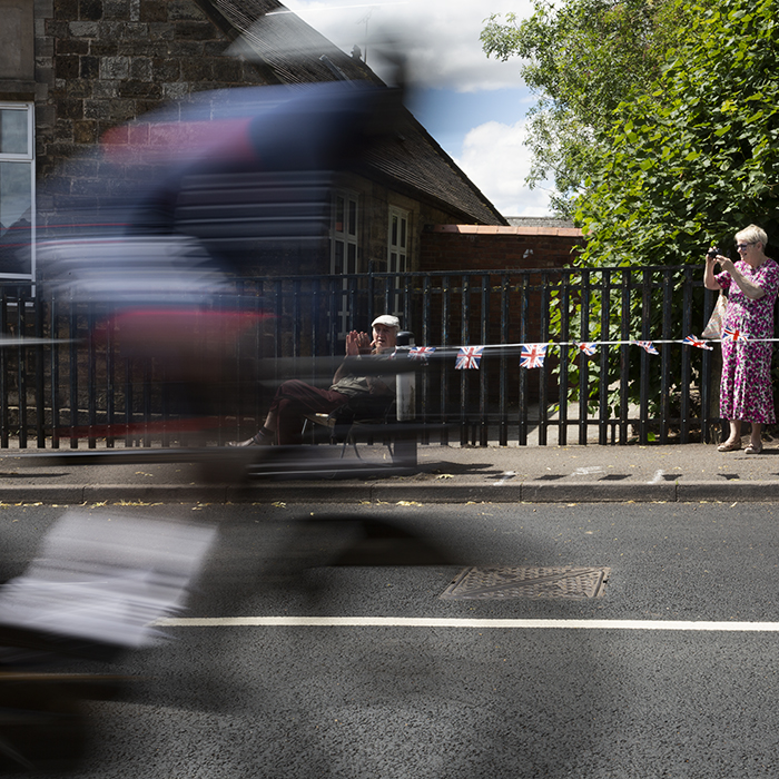 Birmingham 2022 - XXII Commonwealth Games - Men’s Time Trial - A rider from Belize passes in a blur as two older ladies clap