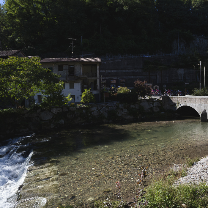 Coppa Bernocchi 2025 -Riders pass down the riverfront near an historic bridge in Castiglione Olona