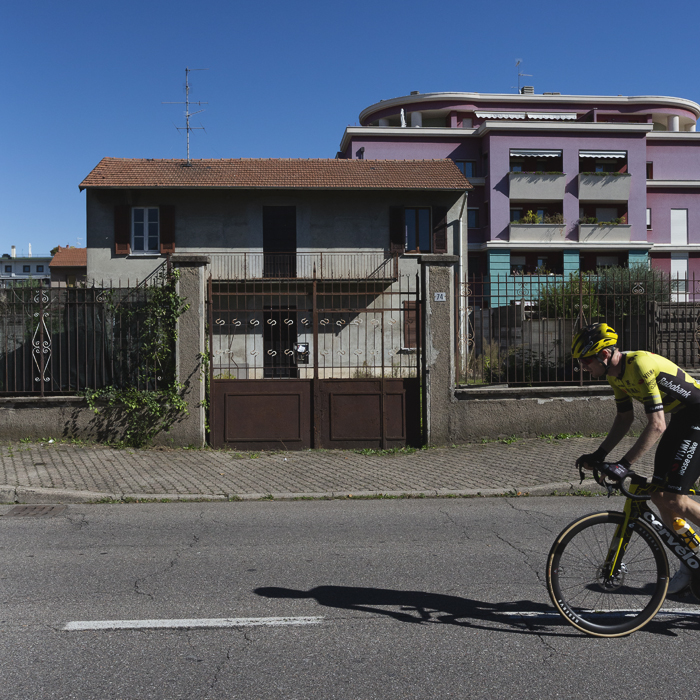 Coppa Bernocchi 2025 - Thomas Gloag rides in front of a set of old gates with more modern buildings visible in the background