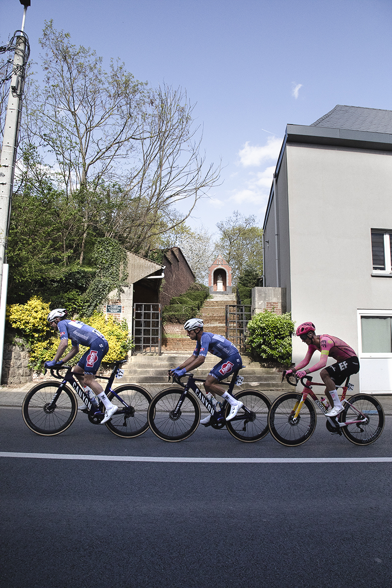 De Brabantse Pijl 2024 - A group of three riders pass a shrine in Overijse