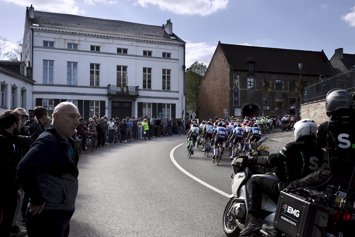 De Brabantse Pijl 2024 - A man with a whistle in his mouth stands at the side of S Bocht as the peloton passes