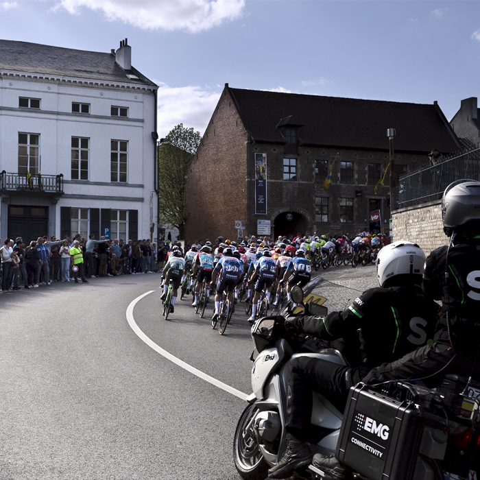 De Brabantse Pijl 2024 - A man with a whistle in his mouth stands at the side of S Bocht as the peloton passes