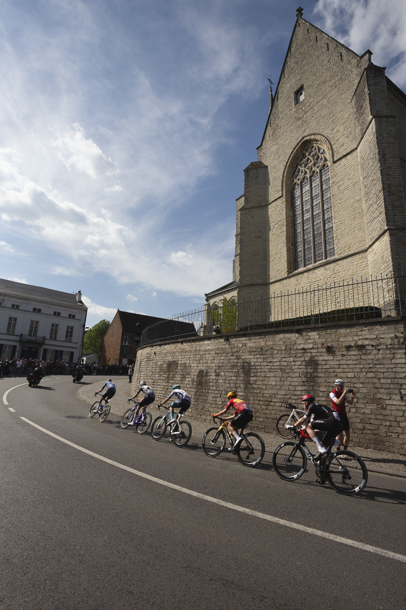 De Brabantse Pijl 2025 - A group of riders pass the church as they begin to take on the climb in Overijse