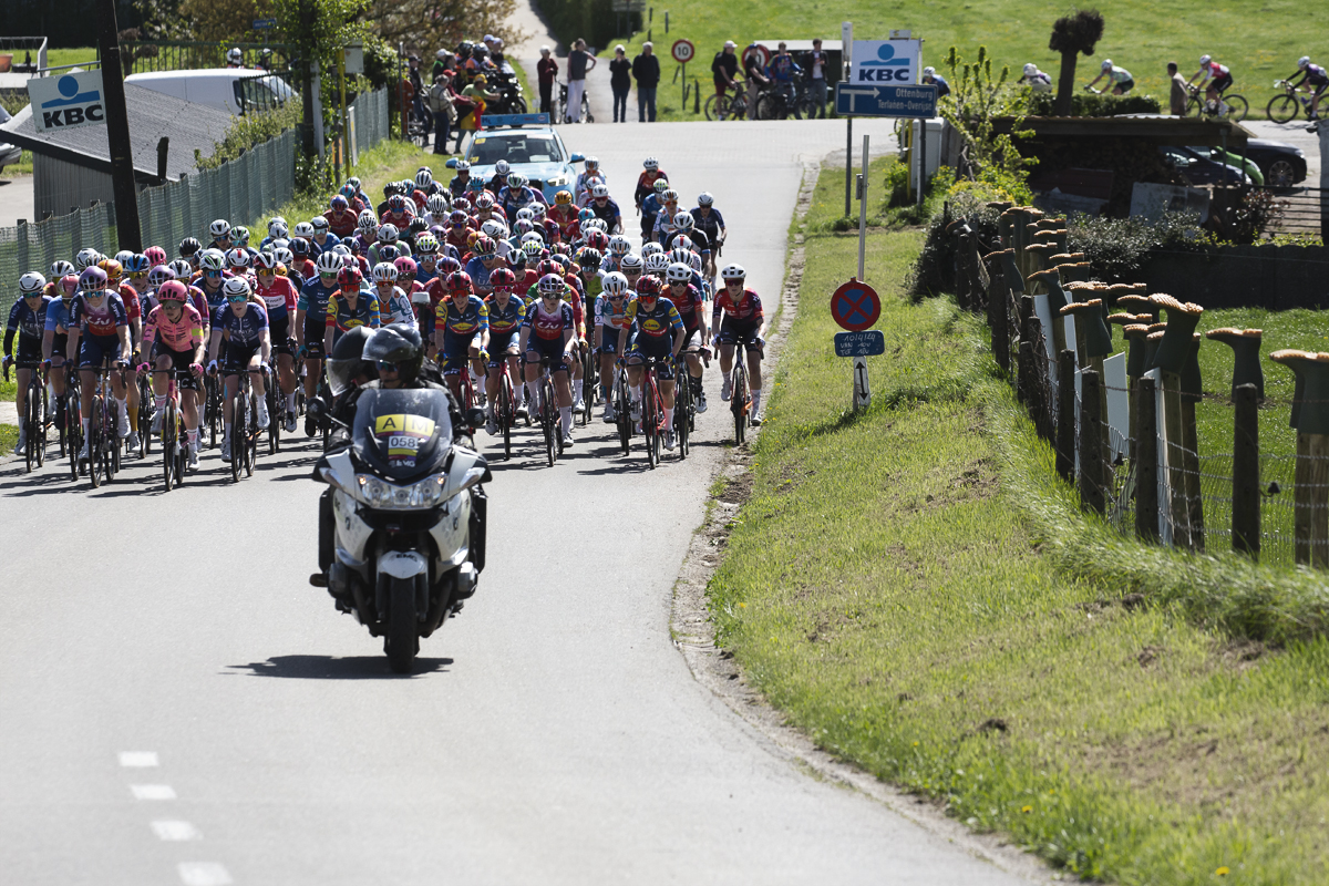 De Brabantse Pijl Vrouwen 2024 - The peloton move up Holstheide past a fence adorned with upside down wellington boots - a symbol of a farmer’s protest
