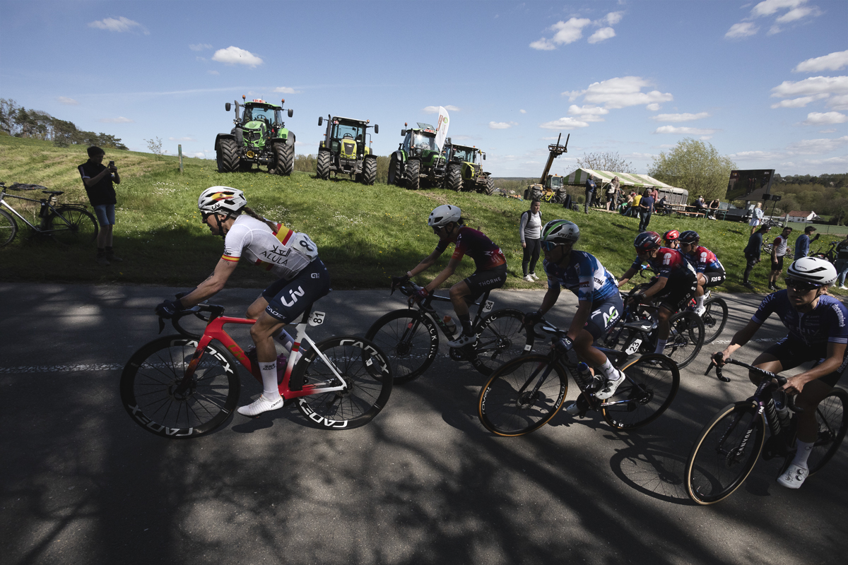 De Brabantse Pijl Vrouwen 2024 - Mavi García of Liv AlUla Jayco wears the Spanish Champion’s jersey as she passes a line of tractors while protesting farmers watch the race