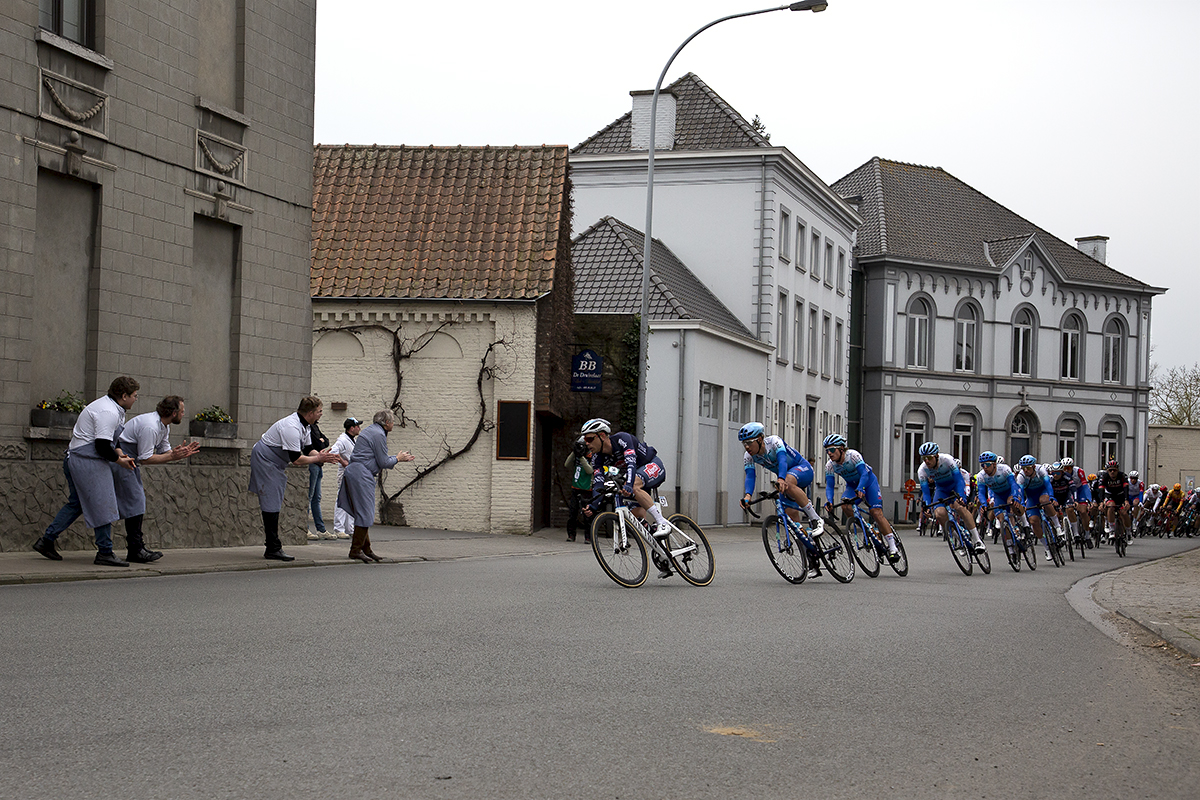 Dwars Door Vlaanderen 2022 - Butchers line the street as Alpecin-Fenix and Team BikeExchange-Jayco lead the peloton past