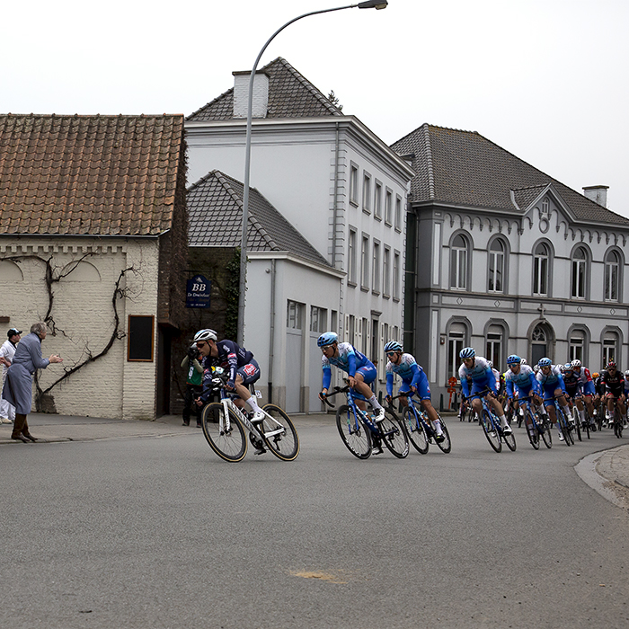 Dwars Door Vlaanderen 2022 - Butchers line the street as Alpecin-Fenix and Team BikeExchange-Jayco lead the peloton past