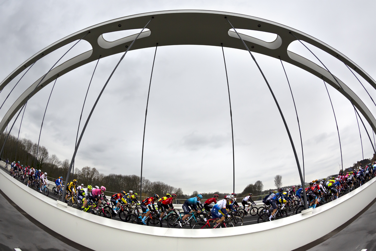 Dwars Door Vlaanderen 2023 - The peloton seen from the side crossing the Munkenbrug