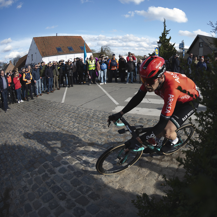Dwars Door Vlaanderen 2024 - Dan McLay rounds a corner watched by fans lining the road