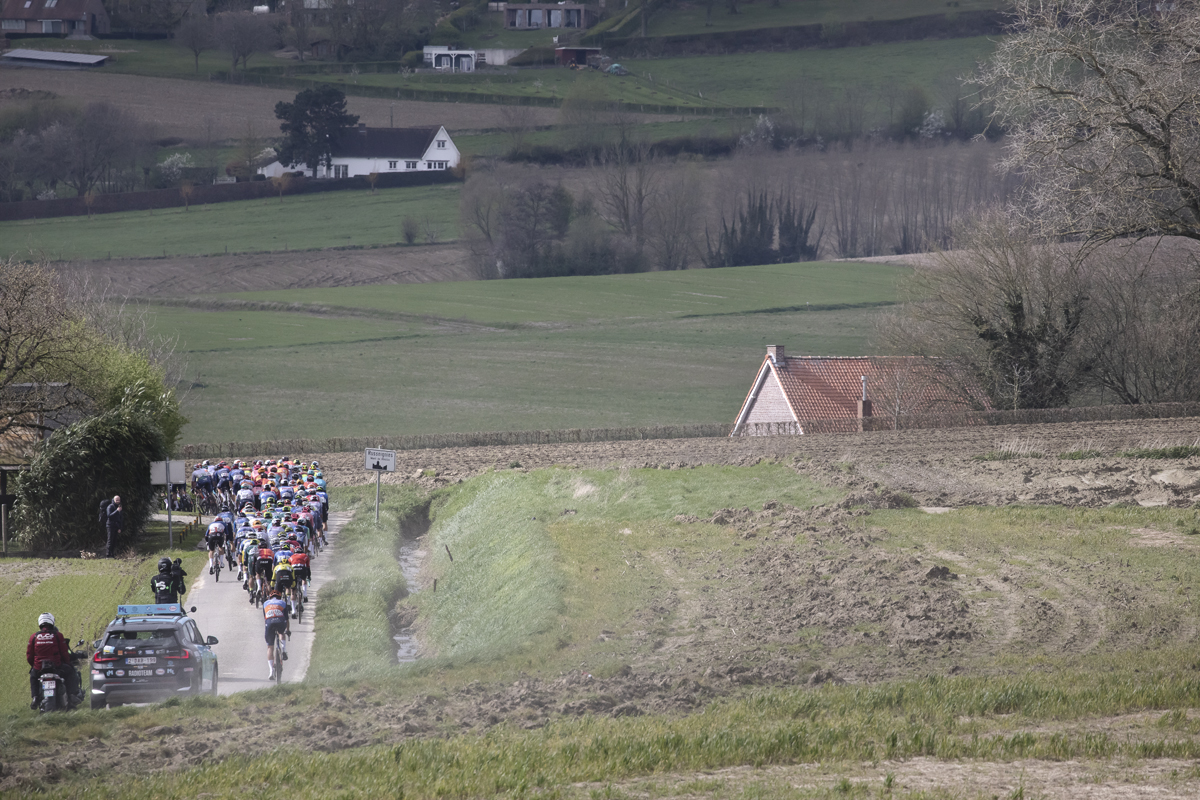 Dwars Door Vlaanderen 2024 - Riders with ploughed fields and a high bank next to them on Rue des Chapelles