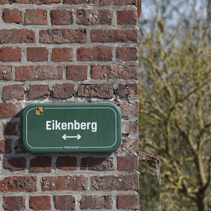 Dwars Door Vlaanderen 2025 - A green sign on a brick wall reads Eikenberg