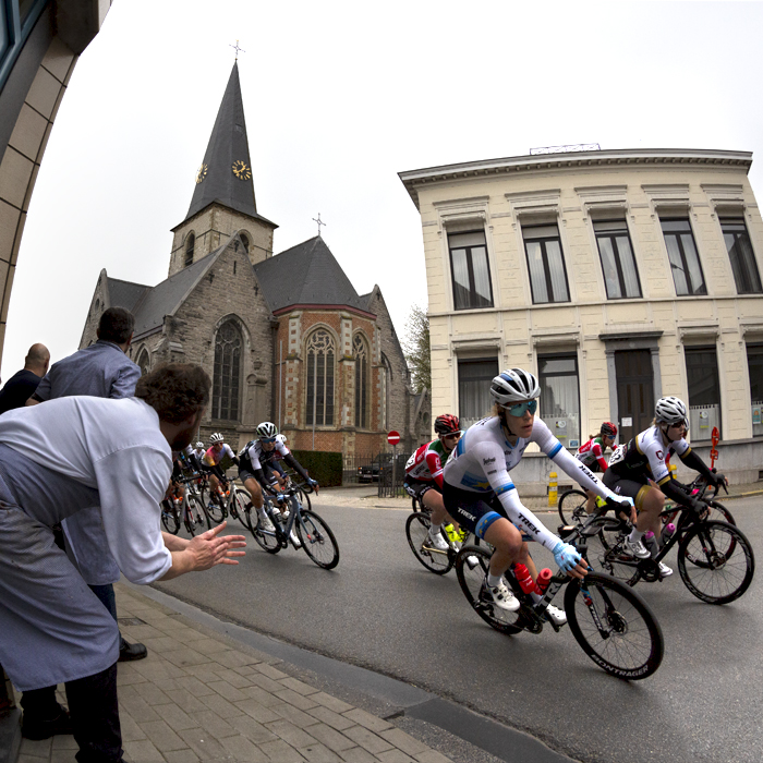 Dwars Door Vlaanderen Vrouwen 2022 - Trek-Segafredo rider Ellen van Dyke in her Euro champions jersey, followed by a group of riders is applauded by a butcher as she passes their shop