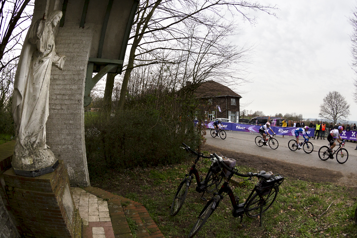 Dwars Door Vlaanderen Vrouwen 2023 - A group of riders go past the shrine