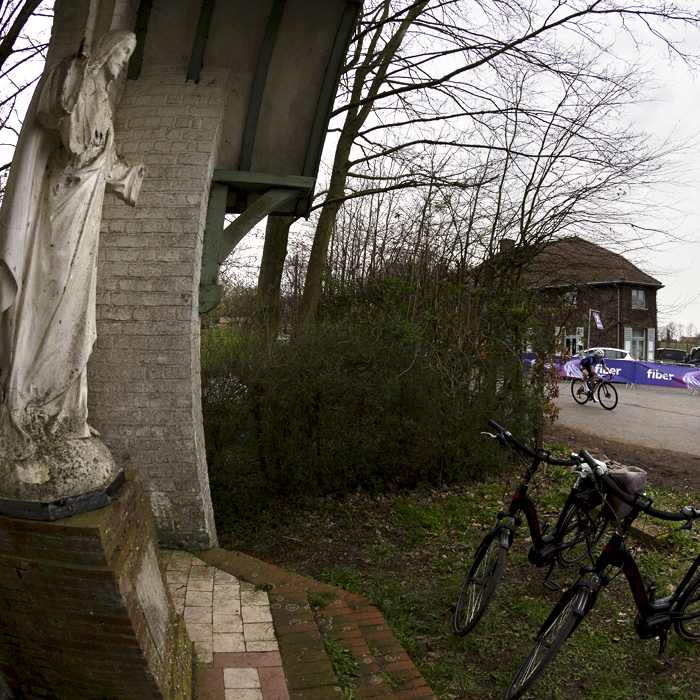 Dwars Door Vlaanderen Vrouwen 2023 - A group of riders go past the shrine