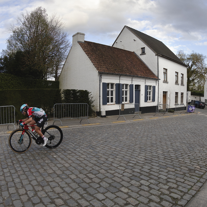 Dwars Door Vlaanderen Vrouwen 2024 - Audrey De Keersmaeker races on the cobbles with white washed buildings behind