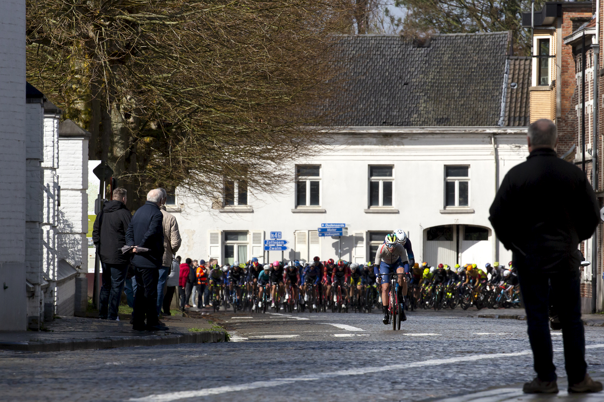 E3 Saxo Classic 2023 - A small group of riders try to break away from the peloton on a cobbled road in a small town