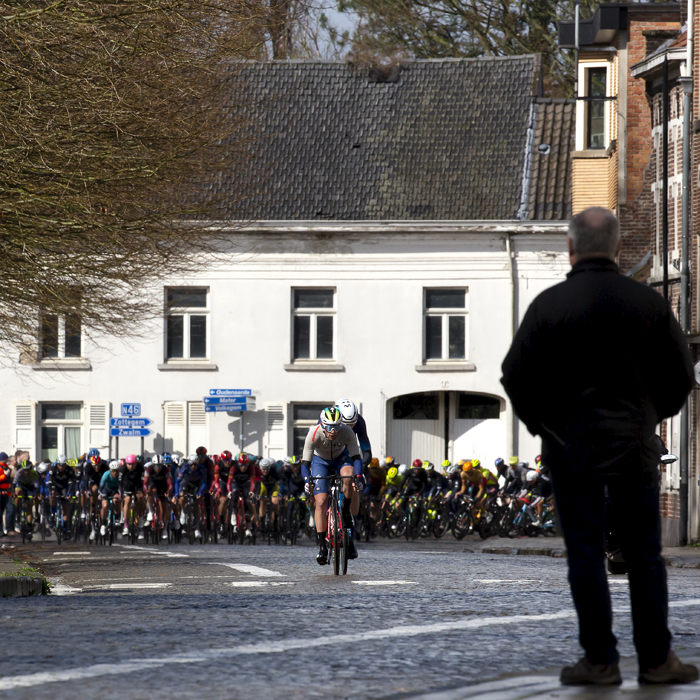 E3 Saxo Classic 2023 - A small group of riders try to break away from the peloton on a cobbled road in a small town