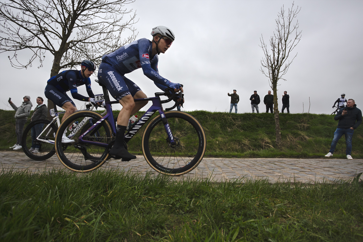 E3 Saxo Classic 2024 - Juri Hollmann and Lewis Askey are watched by fans on a raised bank at the side of Paddestraat