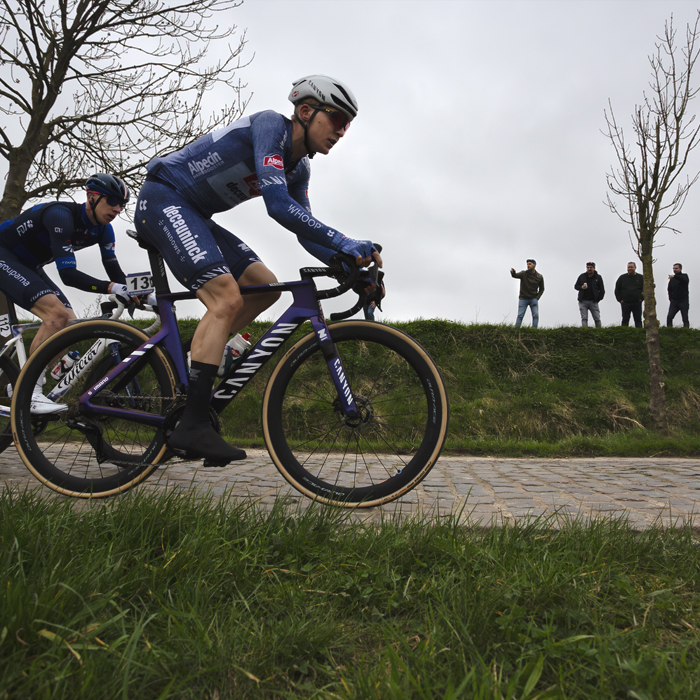 E3 Saxo Classic 2024 - Juri Hollmann and Lewis Askey are watched by fans on a raised bank at the side of Paddestraat
