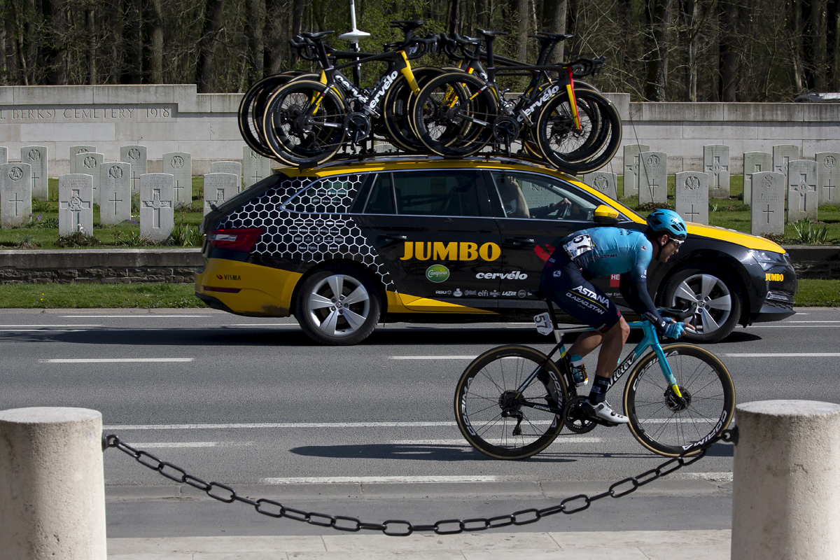 Gent - Wevelgem 2022 - Artyom Zakharov of Astana Qazaqstan Team passes a cemetery with a Jumbo Visma team car