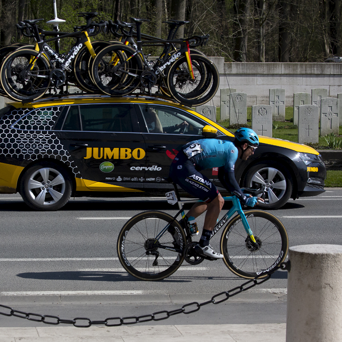 Gent - Wevelgem 2022 - Artyom Zakharov of Astana Qazaqstan Team passes a cemetery with a Jumbo Visma team car