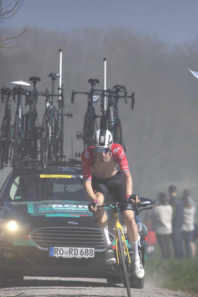 Gent - Wevelgem 2022 - Timo Roosen of Jumbo-Visma with his shirt undone followed closely by a Bora team car on a Ploegsteert