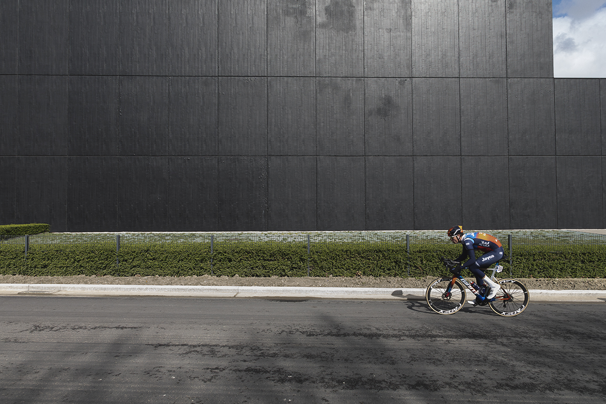 Gent Wevelgem 2024 - A rider passes in front of a large black warehouse in Morsele