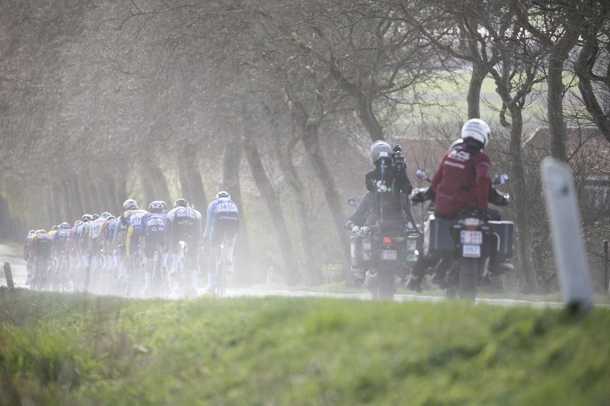 Gent Wevelgem 2025 - Dust is kicked up as a group of riders races down Armentierssteenweg