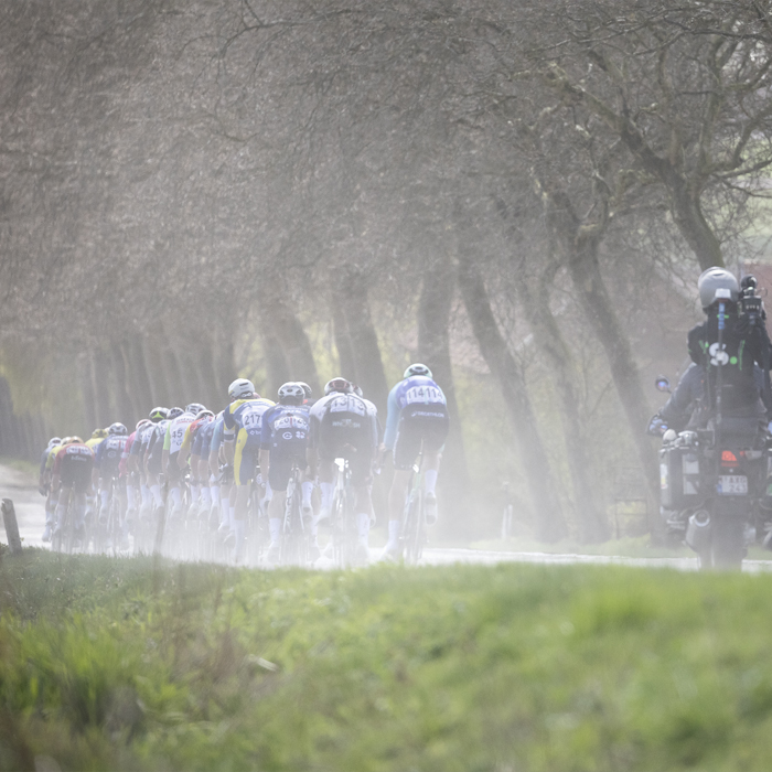 Gent Wevelgem 2025 - Dust is kicked up as a group of riders races down Armentierssteenweg