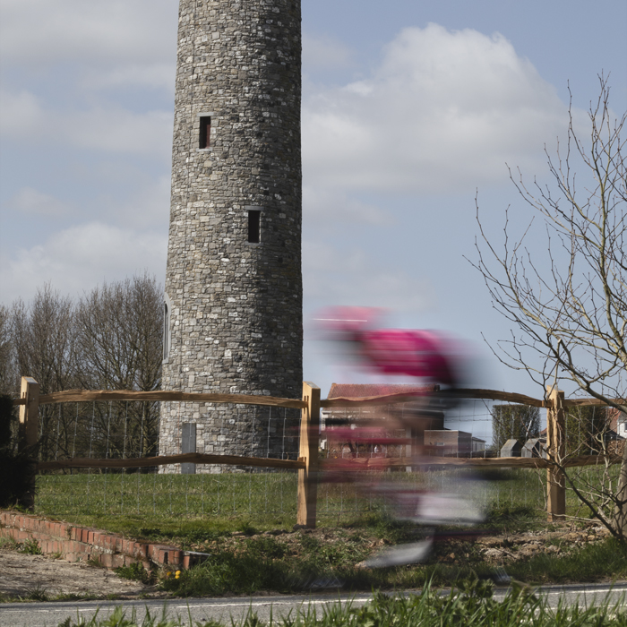 Gent Wevelgem 2025 - A rider speeds past the Irish Peace Tower