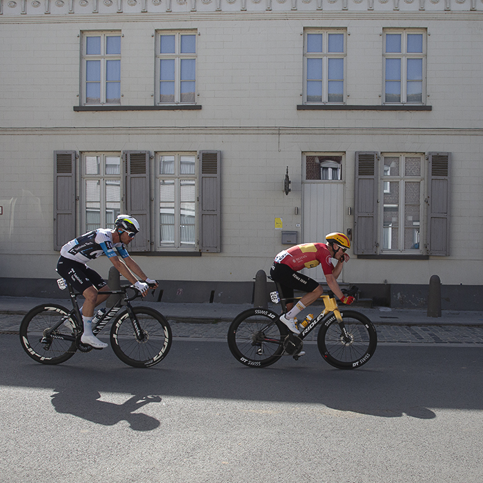 Manlio Moro and Anders Skaarseth ride past a grand old building with shuttered windows