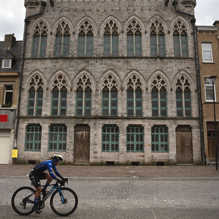 Gent Wevelgem Vrouwen 2024 - Laura Ruiz Pérez rides in front of the grand facade of a Flemish building