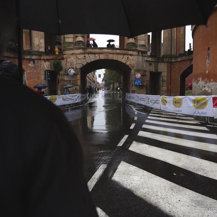 Giro dell’Emilia 2024 - Fans huddle under umbrellas waiting for the next pass of the race under the Arco Del Meloncello