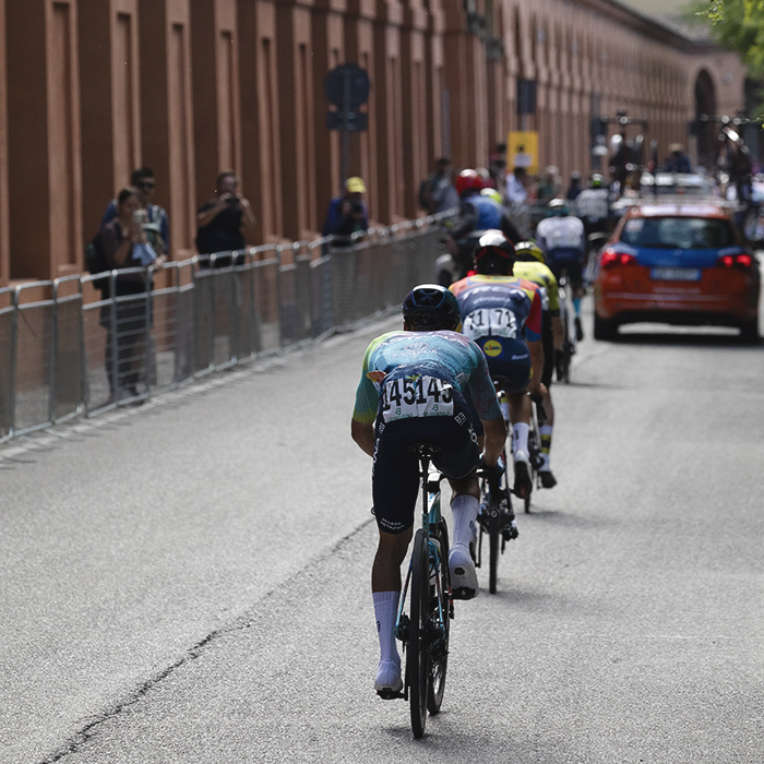Giro dell’Emilia 2025 - Riders from behind on the climb with the Portico stretching out into the distance