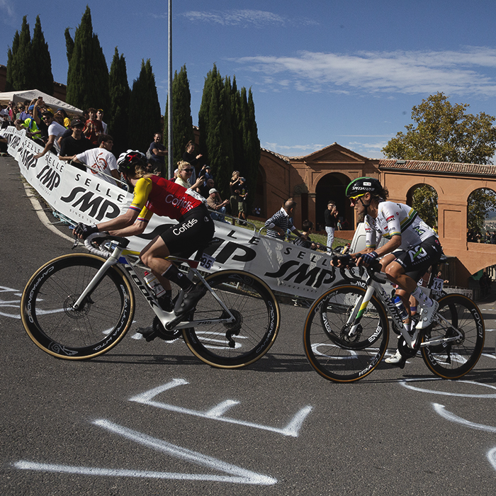 Giro dell'Emilia Internazionale Donne Elite 2025 - Riders pass over chalk messages written on the road on their way up the climb