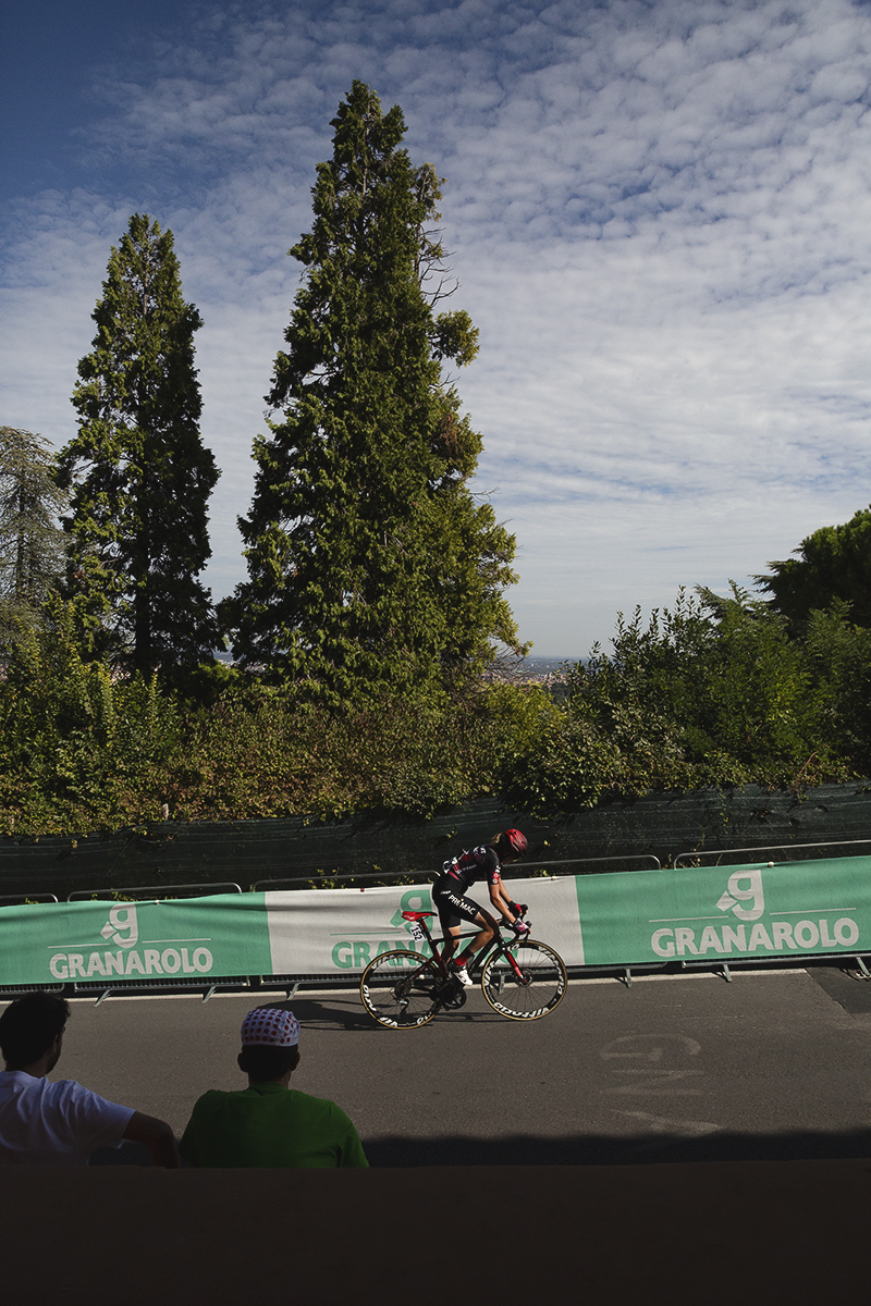 Giro dell'Emilia Internazionale Donne Elite 2025 - Valeria Curnis rides past fans watching from the shade of the portico