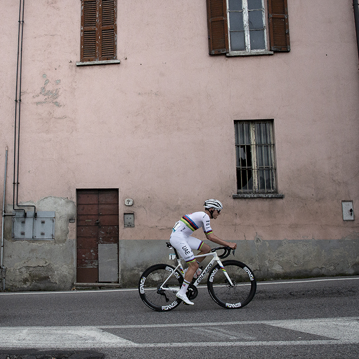 Il Lombardia 2024 - Tadej Pogačar rides past a pastel pink building in Como