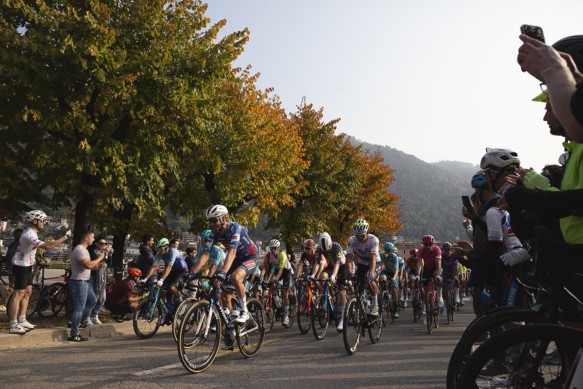 Il Lombardia 2025 - Fans film the peloton as it rolls out along a tree lined avenue in Como