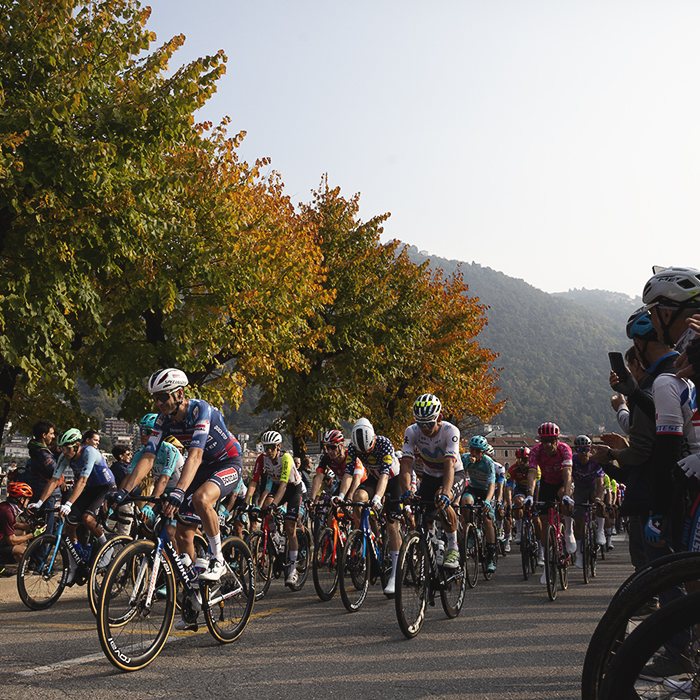 Il Lombardia 2025 - Fans film the peloton as it rolls out along a tree lined avenue in Como