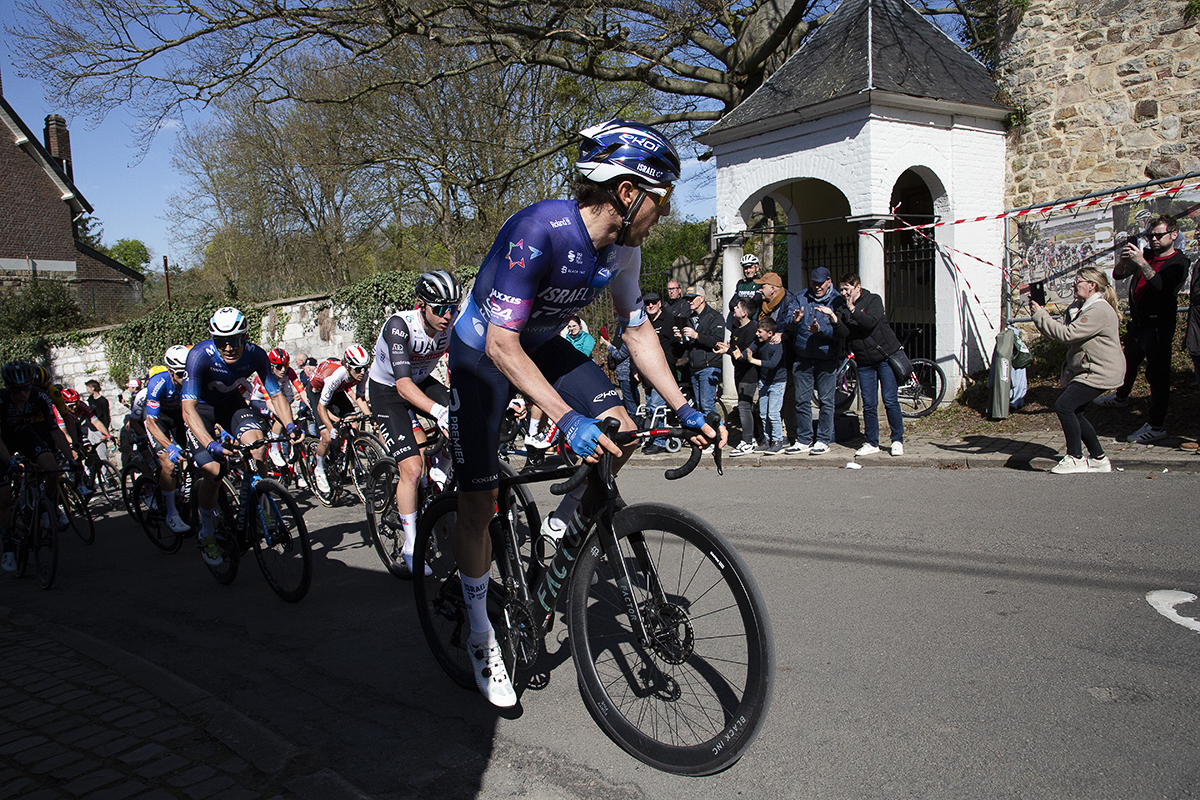 La Flèche Wallonne 2023 - The peloton passes one of the white chapels on the Mur de Huy