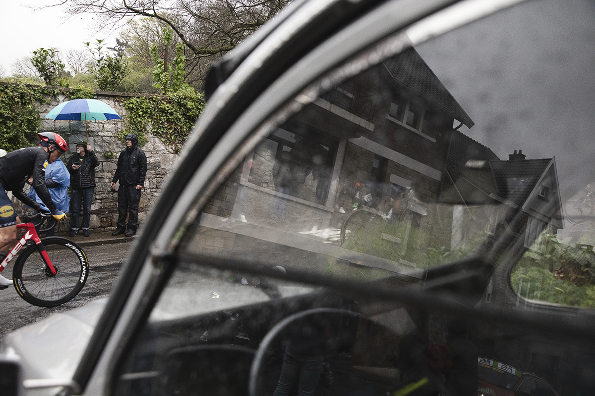 La Flèche Wallonne 2024 - A rider seen through the window of a 2CV on the Mur de Huy