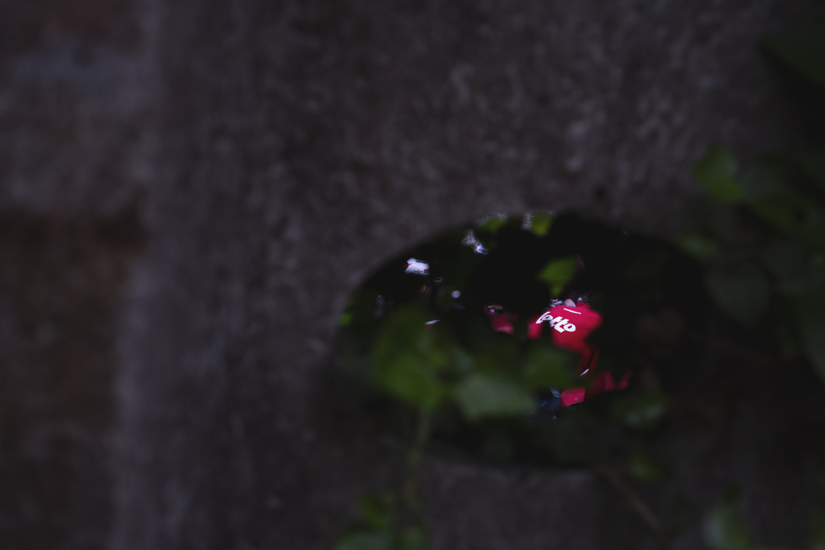 La Flèche Wallonne 2025 - A Lotto rider is seen through the hole in a telegraph pole