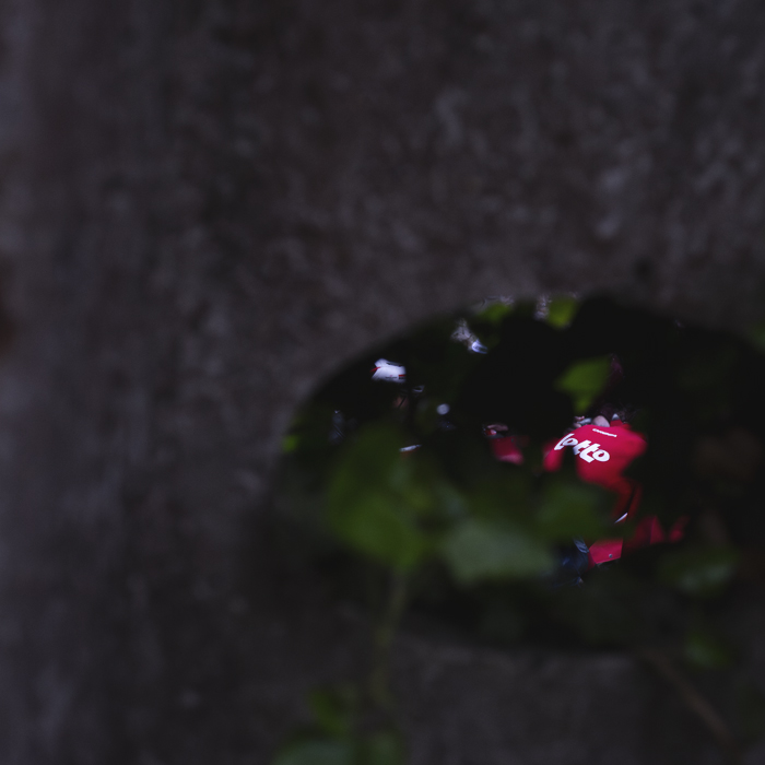 La Flèche Wallonne 2025 - A Lotto rider is seen through the hole in a telegraph pole