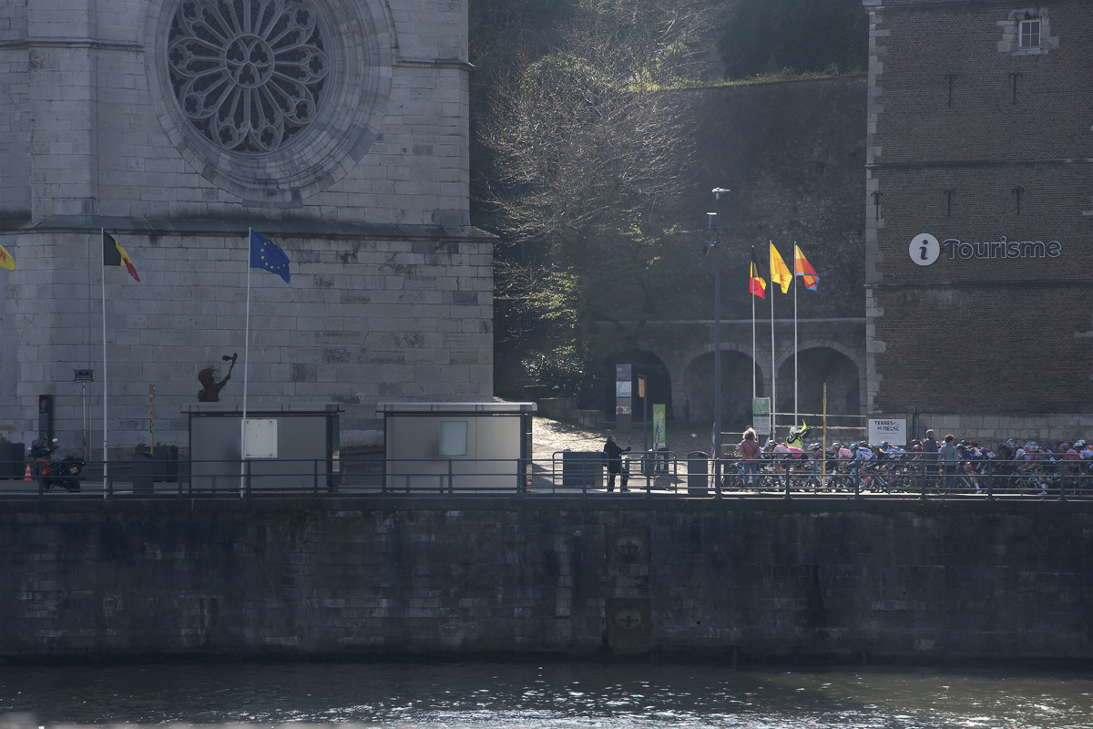 La Flèche Wallonne Femmes 2023 - The peloton is illuminated by a patch of light as it passes near the cathedral in Huy