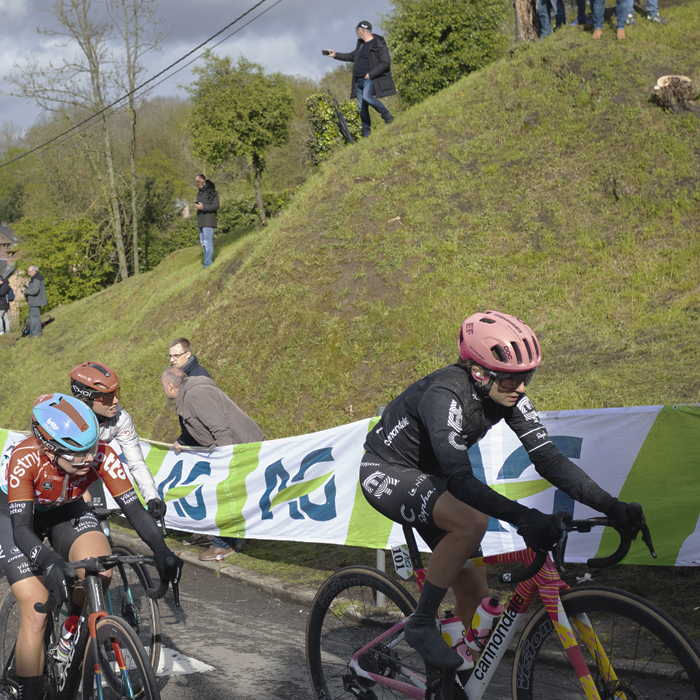 La Flèche Wallonne Femmes 2024 - A group of riders pass a grassy mound on the Mur de Huy
