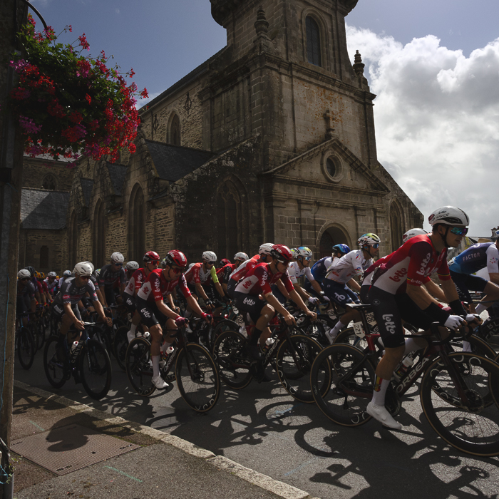 Bretagne Classic - Ouest-France 2025 - The peloton passes in front of the church in Châteauneuf-du-Faou