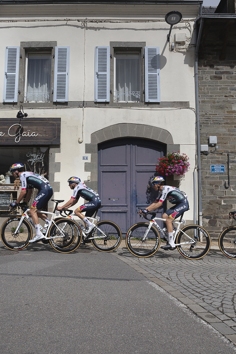 Bretagne Classic - Ouest-France 2025 - The Red Bull - BORA - hansgrohe pass in front of a large arched door in Châteauneuf-du-Faou
